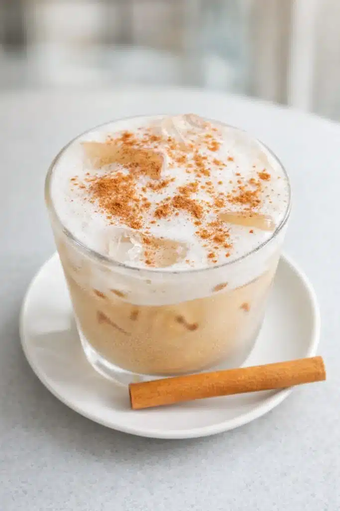 Iced vanilla cinnamon milk tea with cinnamon foam on white saucer
