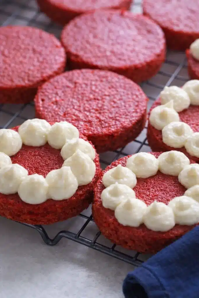 Mini Red Velvet Cakes | Sweet Valentine’s Day Treats 10 Mini red velvet cakes with piped cream cheese frosting on a rack