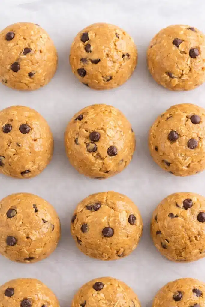 No Bake Protein Balls – Simple and Powerful Snack 11 Rows of no bake peanut butter protein balls with oats and chocolate chips on parchment paper