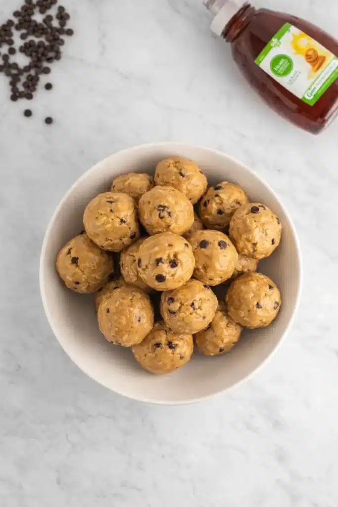No Bake Protein Balls – Simple and Powerful Snack 16 Bowl of no bake peanut butter protein balls with oats and chocolate chips on marble surface