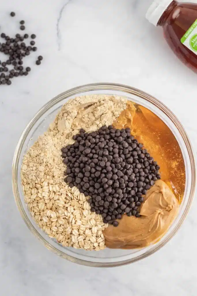 No Bake Protein Balls – Simple and Powerful Snack 12 Glass bowl with peanut butter, oats, honey, protein powder, and chocolate chips for no bake protein balls