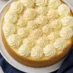 Nutmeg eggnog cheesecake topped with whipped cream and nutmeg on a white plate