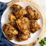 Juicy oven baked chicken thighs on a plate with herbs