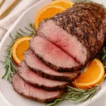 Perfect Christmas Dinner Roast Beef slices with rosemary and orange garnish