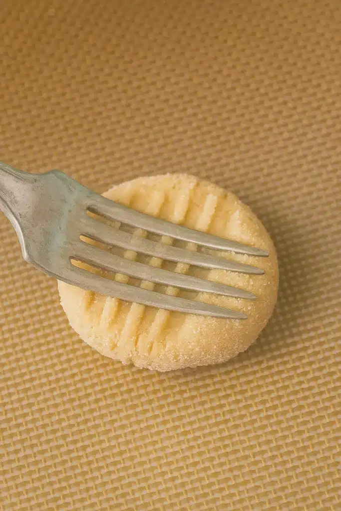 Creating crisscross marks on peanut butter cookie dough with a fork