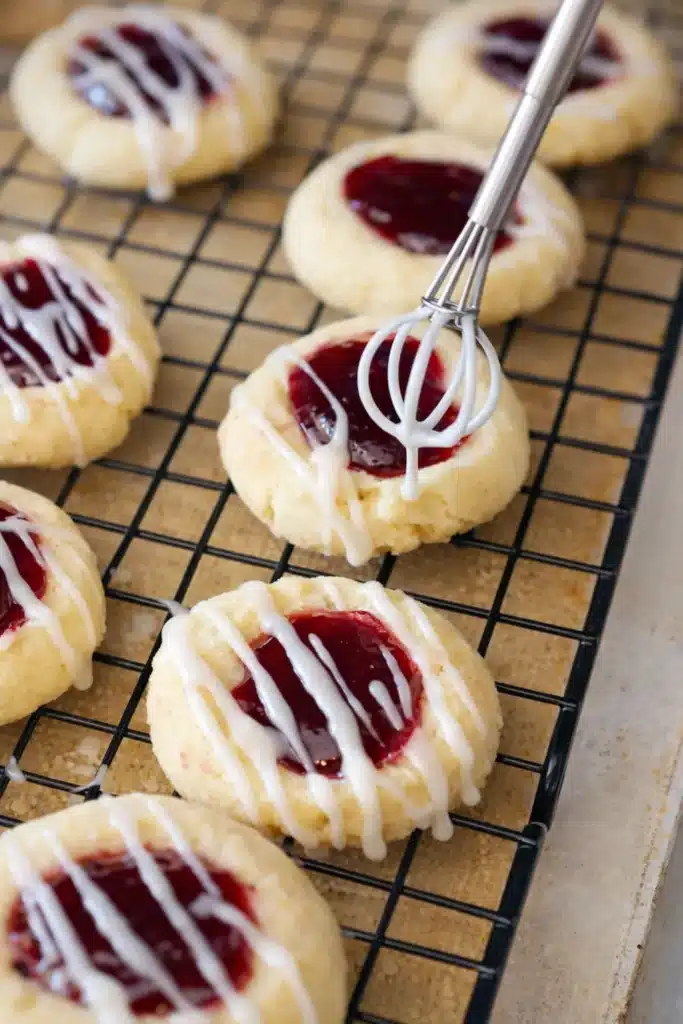 Raspberry Thumbprint Cookies with Icing – Simple Joy 13 Raspberry thumbprint cookies with icing on a cooling rack