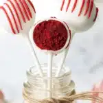 Red velvet cake pops with red drizzle in glass jar on brown wooden table