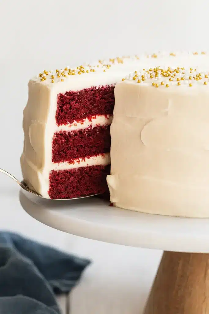 Red Velvet Cake | Amazing, Soft & Vibrant Dessert 7 Red velvet cake slice being lifted to show layers and cream cheese frosting