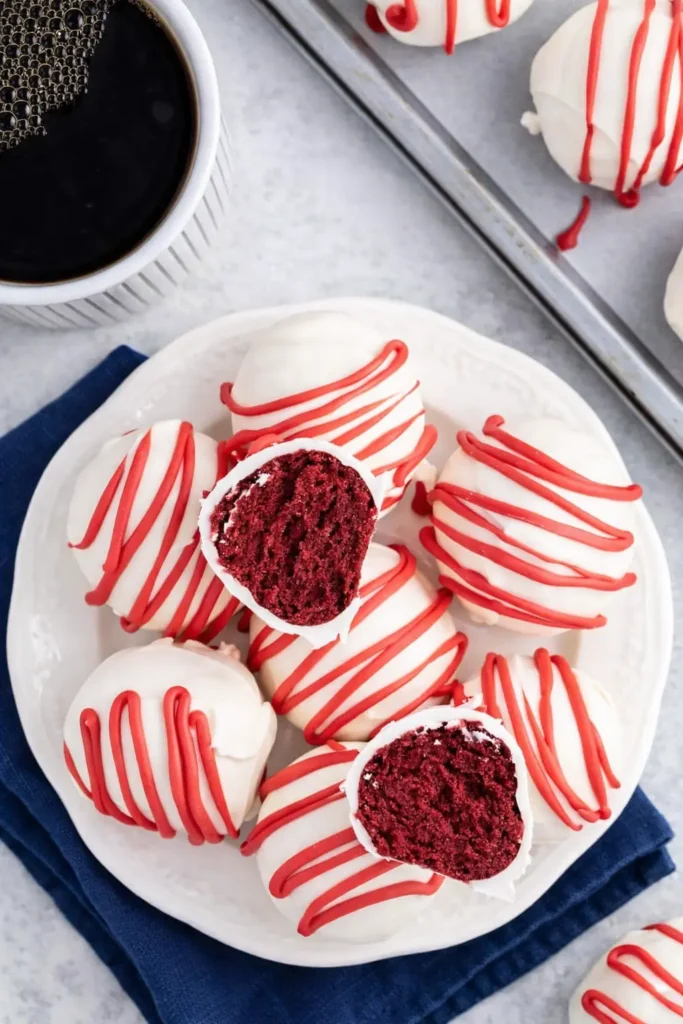 Red velvet cheesecake bites with red drizzle on white plate and dark blue napkin