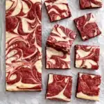 Red velvet cheesecake brownies with creamy swirls on a dark surface
