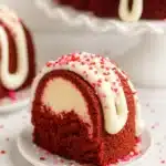 Red velvet cream cheese bundt cake slice with icing and heart sprinkles
