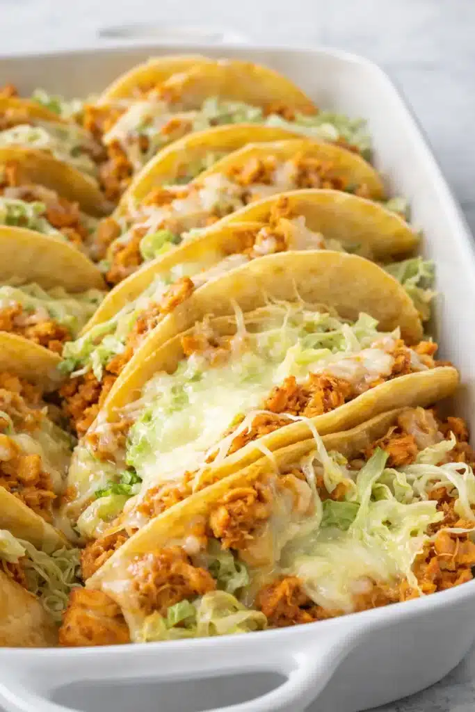 Rotisserie chicken tacos with melted cheese and lettuce in baking dish