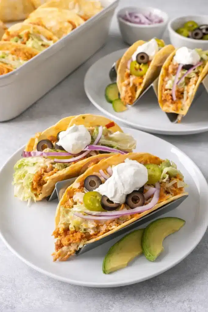 Rotisserie chicken tacos with toppings and avocado slices on white-gray table