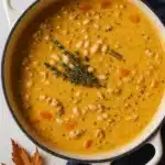 Creamy turkey pumpkin white bean chili in a white pot with herbs
