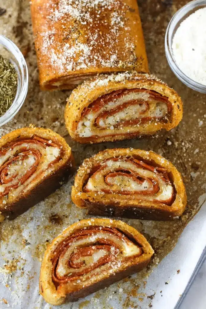 Pepperoni Rolls | Amazing Quick Dinner Recipe 8 Sliced pepperoni rolls on white-gray parchment paper with cheese and herbs