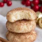 Stack of white cheese cookies with a bitten top cookie on a white surface
