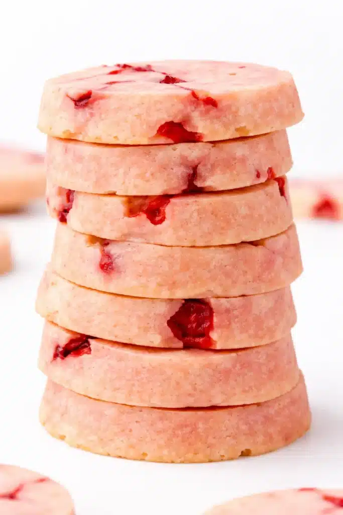 Stack of pink cherry almond shortbread cookies on a white background