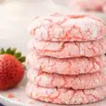 Stack of pink strawberry cake mix cookies coated in powdered sugar