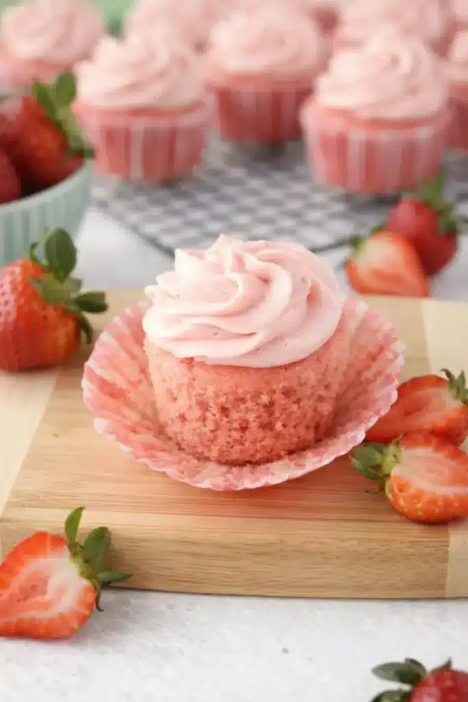 Strawberry cupcake with pink frosting and fresh strawberries on a marble surface