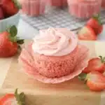 Strawberry cupcake with pink frosting and fresh strawberries on a marble surface