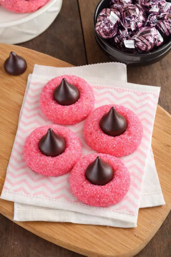Top-down view of strawberry kiss cookies with chocolate truffles on white napkin