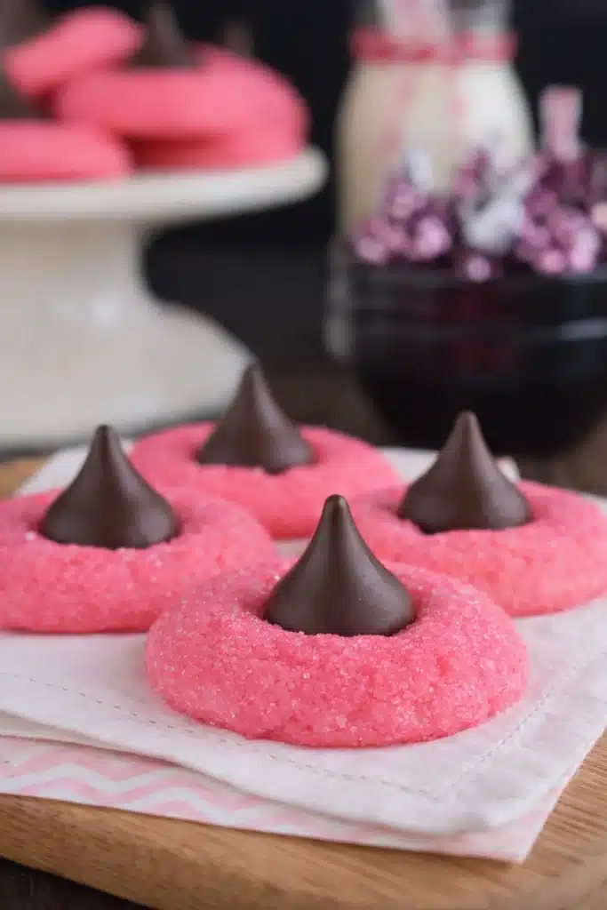 Pink strawberry kiss cookies topped with chocolate truffles on white napkin