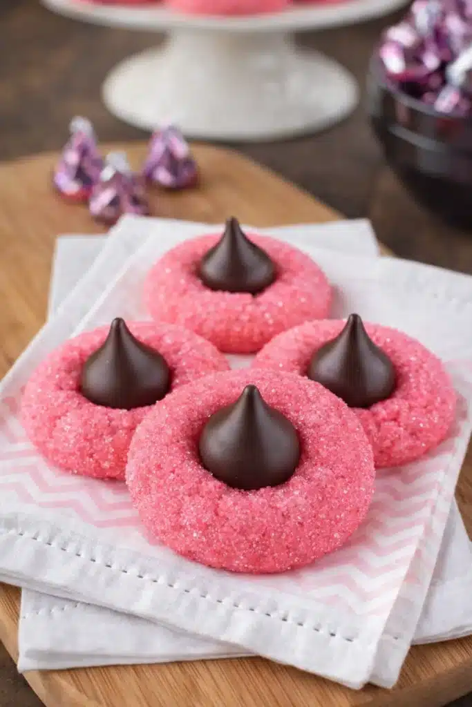Pink strawberry kiss cookies topped with chocolate truffles on white napkin
