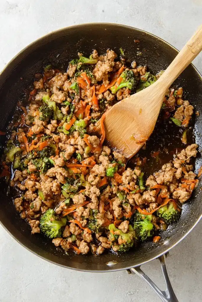 Teriyaki turkey with broccoli and carrots simmering in a skillet