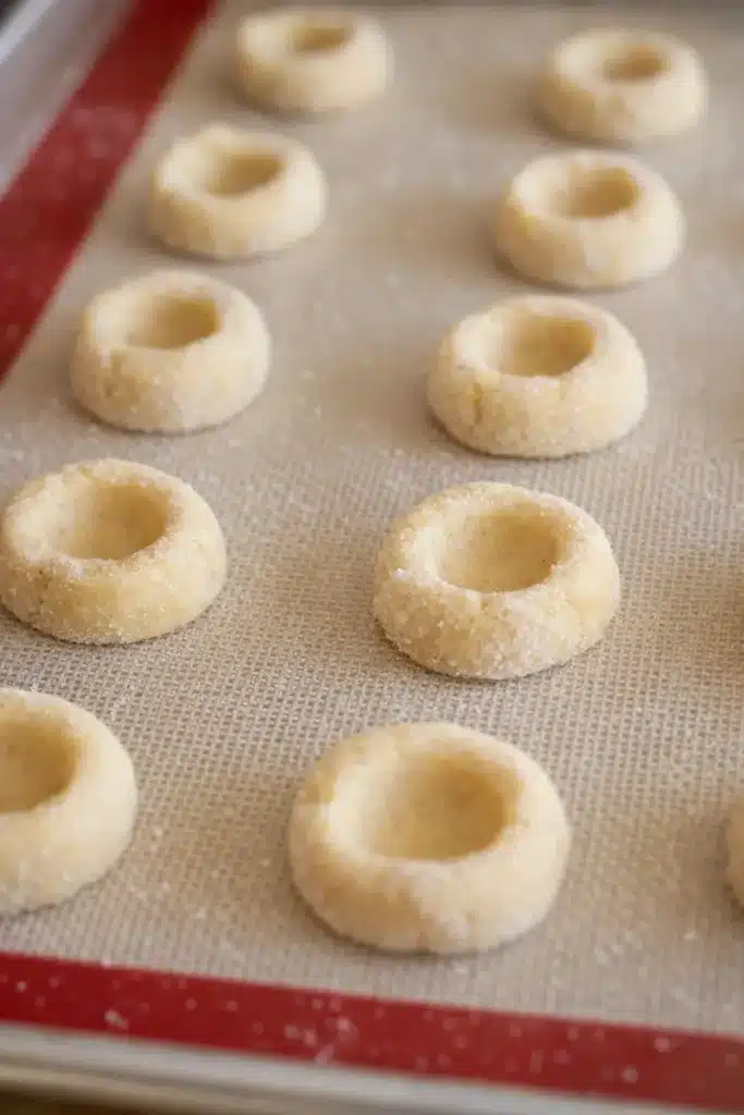 Raspberry Thumbprint Cookies with Icing – Simple Joy 9 Unbaked raspberry thumbprint cookie dough on baking sheet