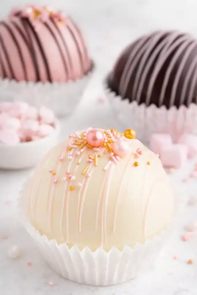 Valentine’s Hot Chocolate Bombs | Easy, Romantic & Fun 10 White and pink Valentine’s hot chocolate bombs with sprinkles on marble