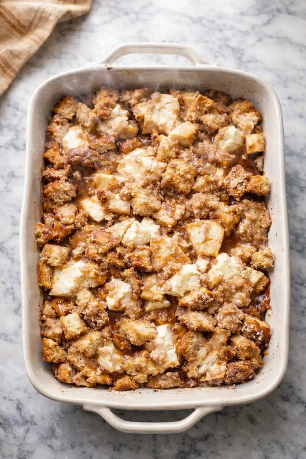 Baked cream cheese French toast casserole with golden crumb topping in white dish