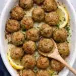 Juicy baked turkey meatballs in a white baking dish with lemon and parsley