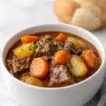Beef stew in red wine sauce with carrots and potatoes in a white bowl