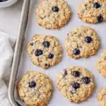 Chewy blueberry oatmeal cookies on baking tray with fresh blueberries