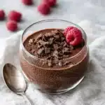 Chocolate chia pudding in glass cups with raspberries and chocolate shavings