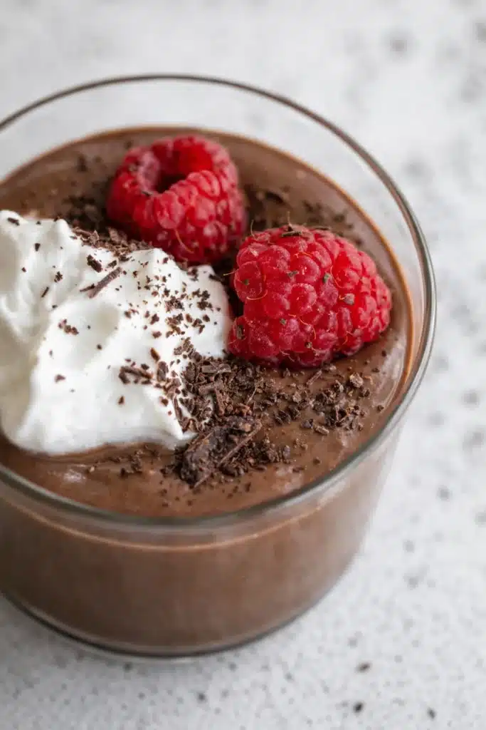 Chocolate Protein Pudding: Creamy, Quick, and Packed with Protein 5 Chocolate protein pudding with whipped cream, raspberries, and chocolate shavings