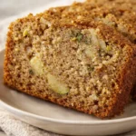 Slice of cozy spiced apple zucchini bread on white plate with soft crumb