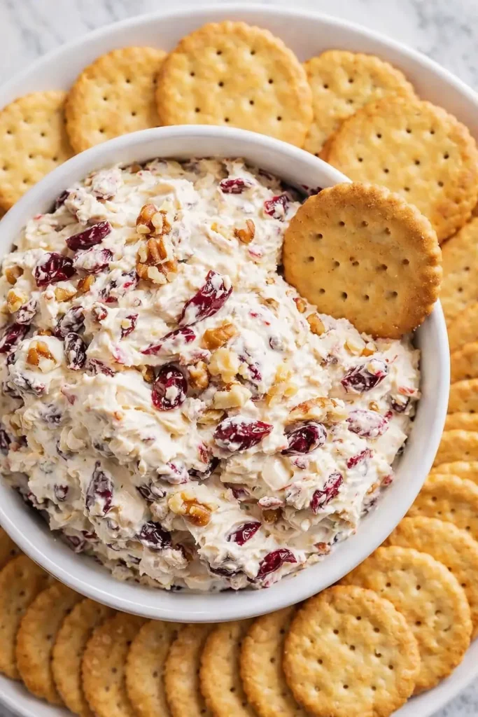 Creamy cranberry walnut cream cheese dip with crackers on a platter