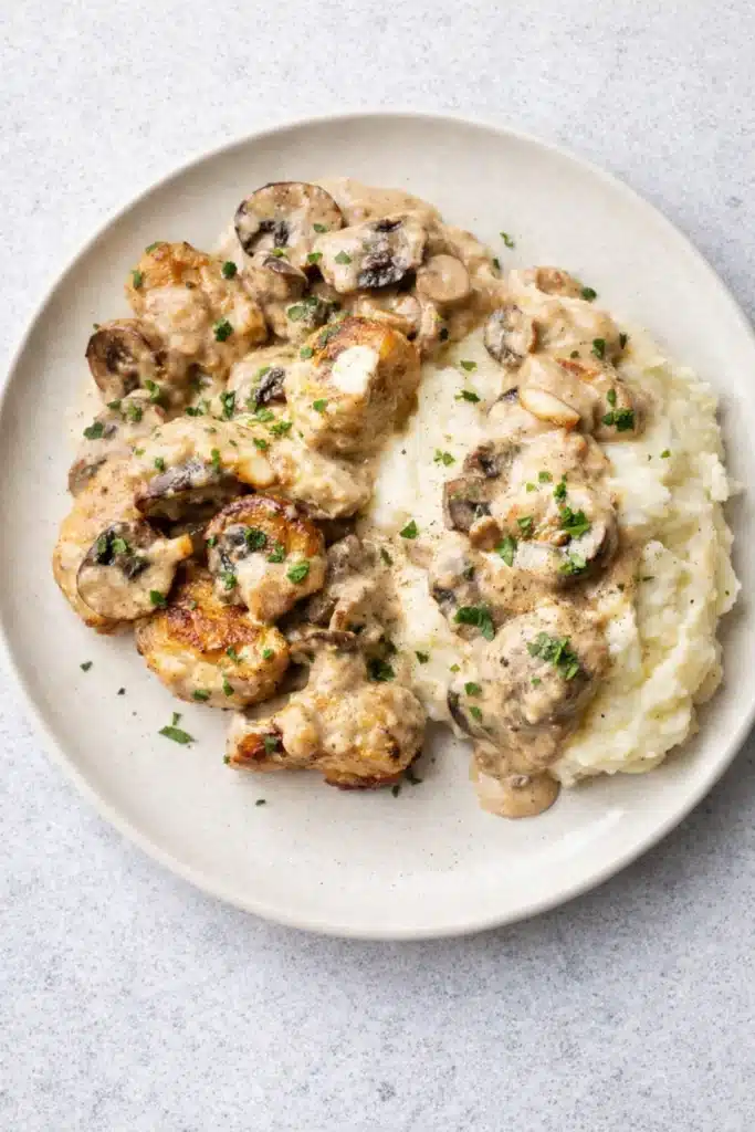 Creamy chicken stroganoff with mashed potatoes on ceramic plate