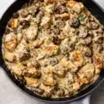 Creamy chicken stroganoff with mushrooms in a skillet on a light surface