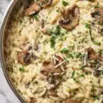 Creamy orzo with mushrooms in skillet topped with parsley and Parmesan