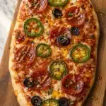Delicious Hot Honey Flatbread Pizza topped with pepperoni, jalapeños, and olives on a wooden board