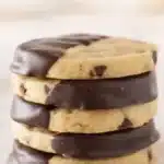 Stack of chocolate chip shortbread cookies dipped in dark chocolate on a light background