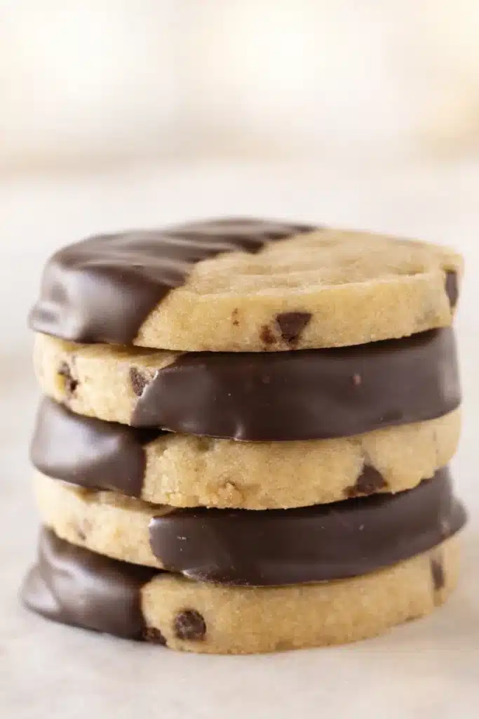 Stack of chocolate chip shortbread cookies dipped in dark chocolate on a light background