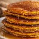 Fluffy pumpkin pancakes with maple syrup dripping on a rustic breakfast plate