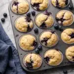 Homemade blueberry protein muffins in a baking tray with fresh blueberries