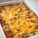 Golden homemade breakfast casserole with cheese, sausage, and peppers in a white baking dish