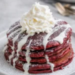 Stack of IHOP red velvet pancakes with cream cheese glaze and whipped cream