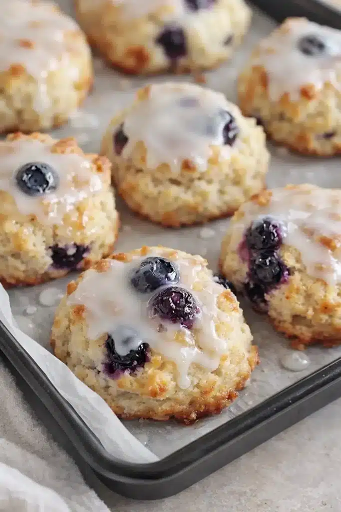 Golden blueberry biscuits with sugar glaze on baking tray