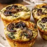 Spinach and mushroom quiche muffins on a plate under warm light